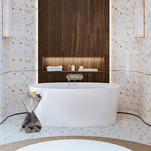 A bathtub fitted with a three-hole wall-mounted bath faucet in a beige bathroom with a beige wall.